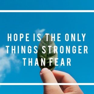 A hand holding a green leaf against a blue sky, with the text "Hope is the only thing stronger than fear" written on it.