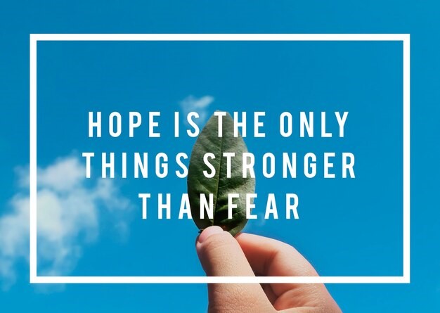 A hand holding a green leaf against a blue sky, with the text "Hope is the only thing stronger than fear" written on it.
